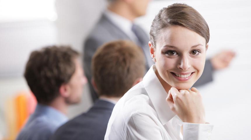 Young businesswoman smiling in a meeting with her colleagues in background